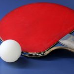 Eine rote Tischtenniskelle neben einem Tischtennisball