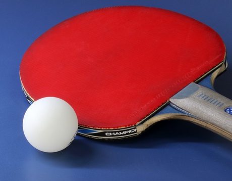Eine rote Tischtenniskelle neben einem Tischtennisball